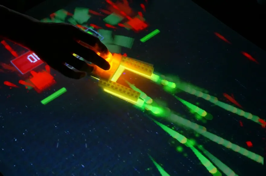 LITTAI at Maker Faire Tokyo 2015: glowing LEGO blocks trailing coloured light across a dark projection surface.